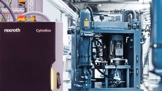 Das Foto zeigt eine Bosch Rexroth CytroBox neben einem Hydraulikaggregat in einer gut beleuchteten Produktionshalle, beides als exemplarische Lösungen in der Industriehydraulik.